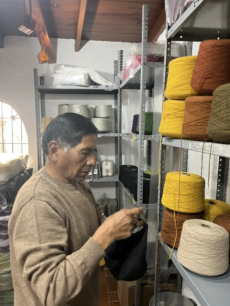 Félix Huaracha en el taller, entre conos de hilo